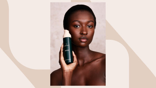 A mid-shot of a black model with short hair holding a bottle of the Salvaterra Universal Serum